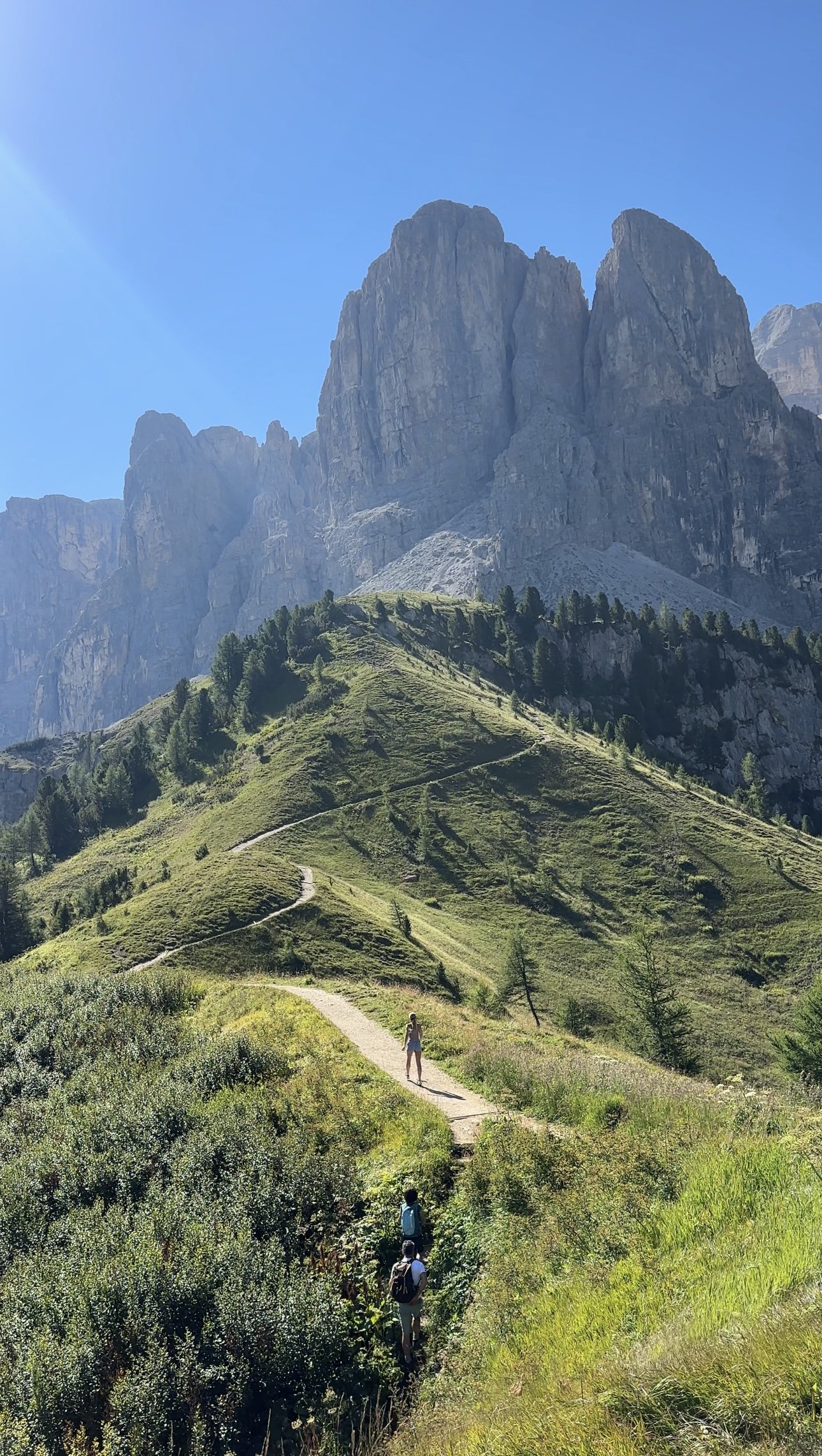 Hikers ascending a mountain trail toward dramatic rock faces